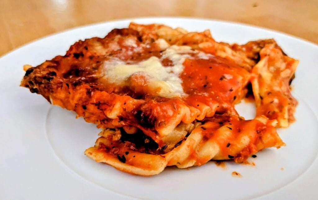 A slice of Bremer frozen lasagna from Aldi sitting on a white plate.