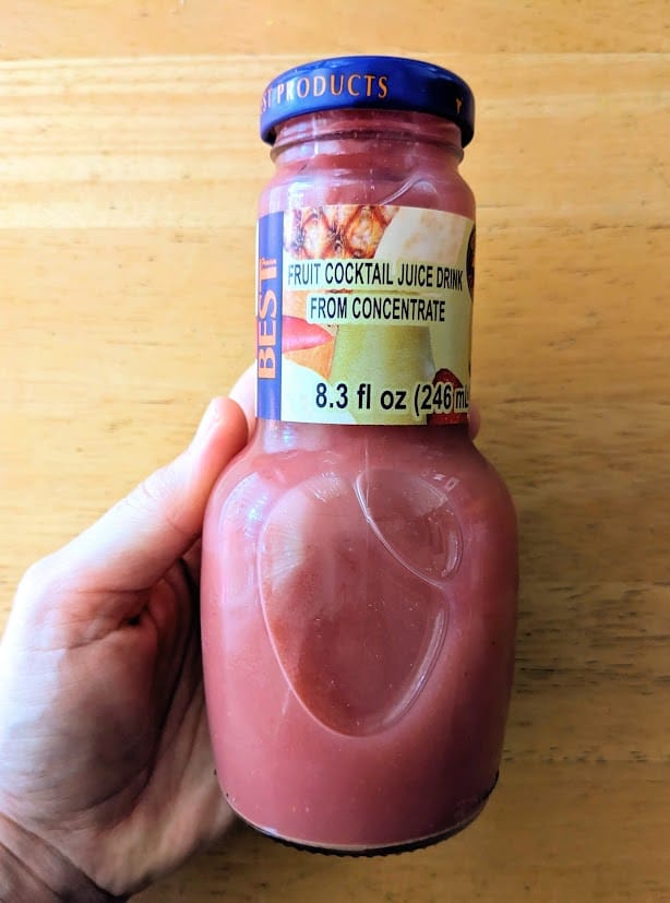 A hand holding a glass bottle of Fruit Cocktail Juice from BEST (brand) Egypt Canning Company.