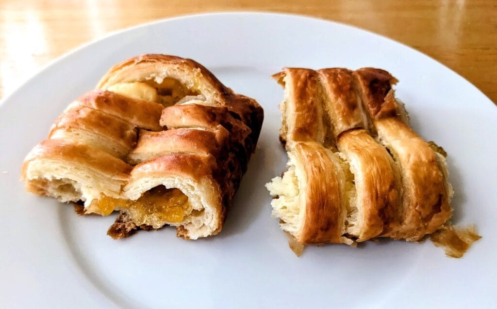 Two halves of a Costco Peaches and Cream Pastry on a white plate.