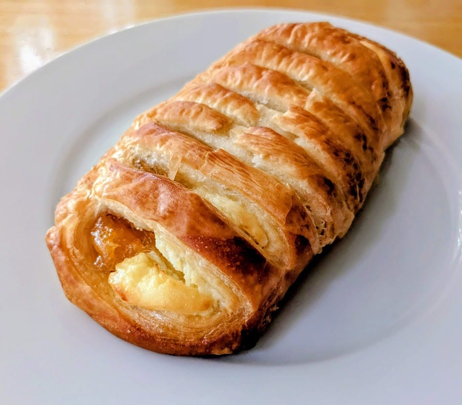 A white plate with a whole Peaches and Cream Pastry from the Costco Bakery.