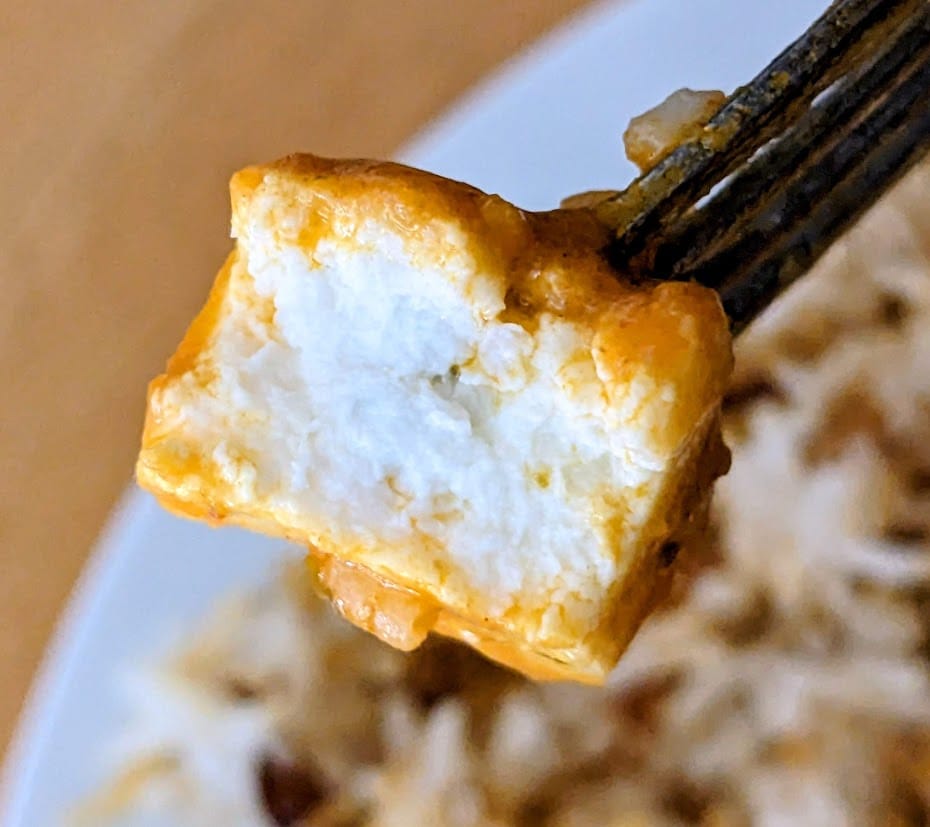 A fork holding a bitten piece of paneer cheese from a Deep Indian Kitchen frozen meal.