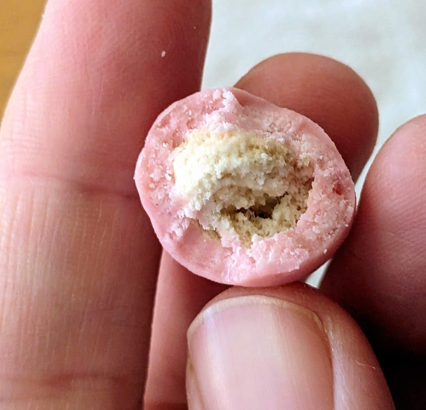 Fingers holding a bitten Strawberry Shortcake Bite from Edward Marc Chocolatiers.
