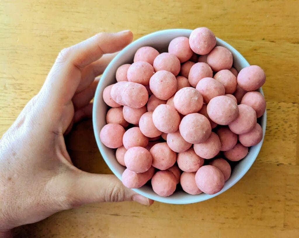 A hand holding a white bowl filled with Edward Marc Strawberry Shortcake Bites from Costco.