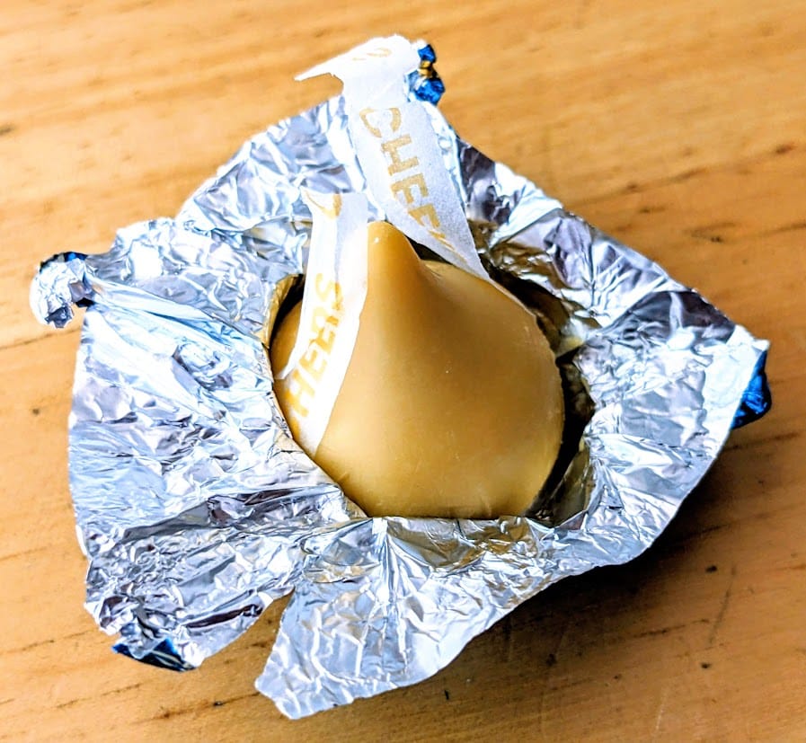 An open foil wrapper surrounding a Hershey's Butterbeer Kiss.