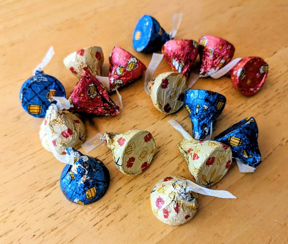 A pile of blue, red, and yellow wrapped Hershey's Butterbeer Kisses on a kitchen table.