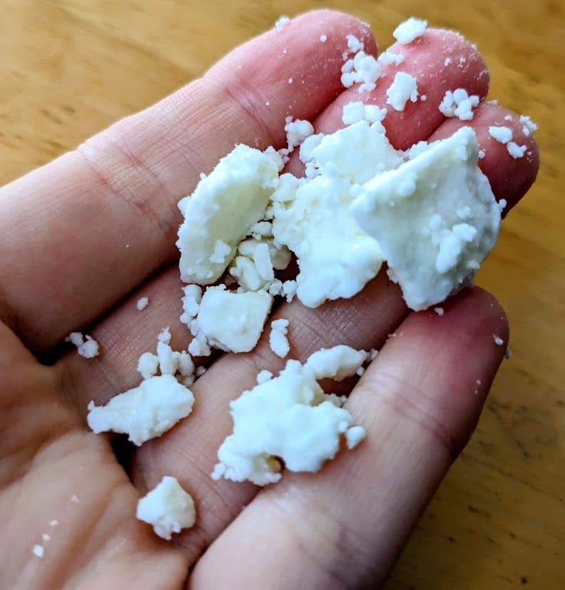 A hand holding crumbled Feta from President brand.