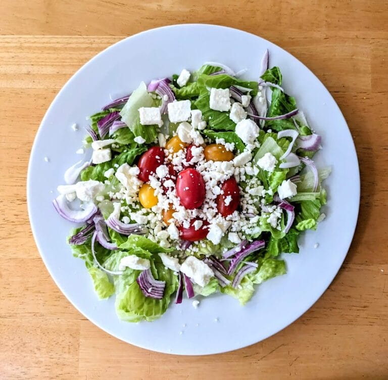 A white plate with a salad topped with President Feta Crumbles.