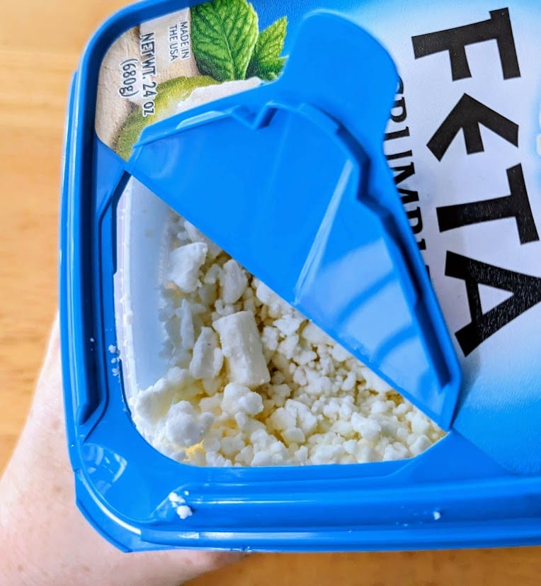 The "shaker top" opening on a plastic tub of President Feta Crumbles from Costco.
