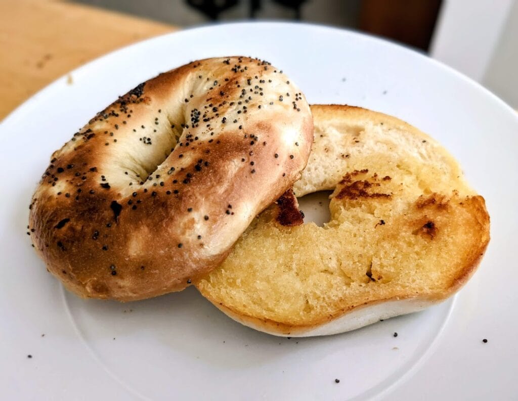 A buttered and toasted Publix Greenwise Onion Bagel, sitting on a white plate.