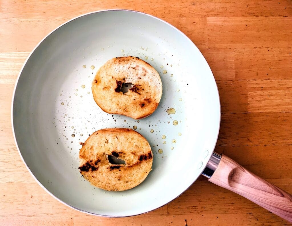 A ceramic pan with two halves of a toasted bagel.