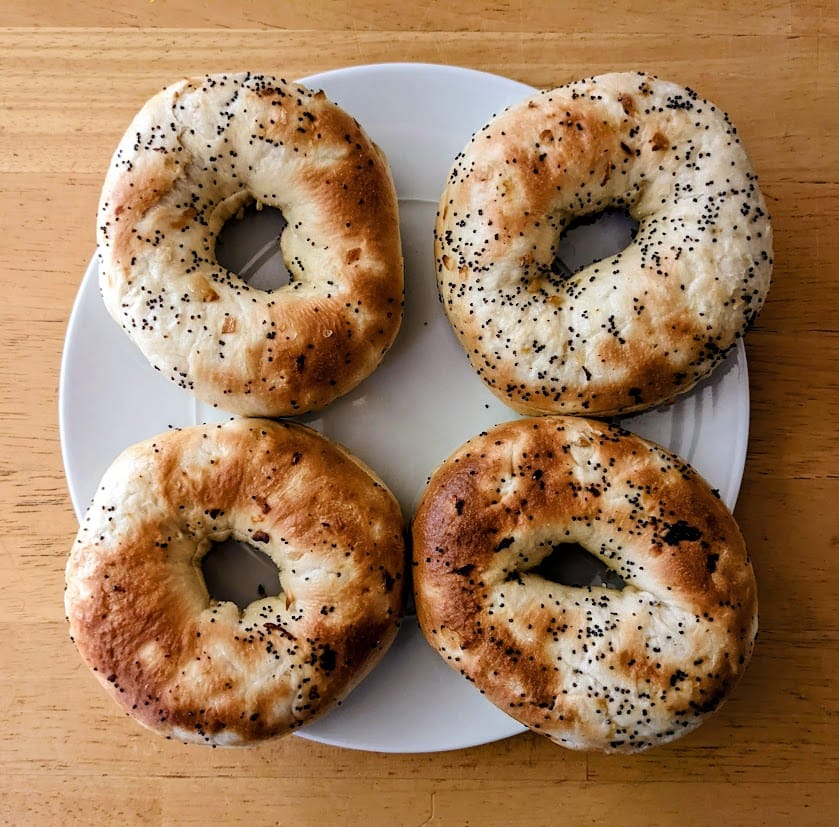 Four Publix Greenwise Onion Bagels sitting on a white plate.
