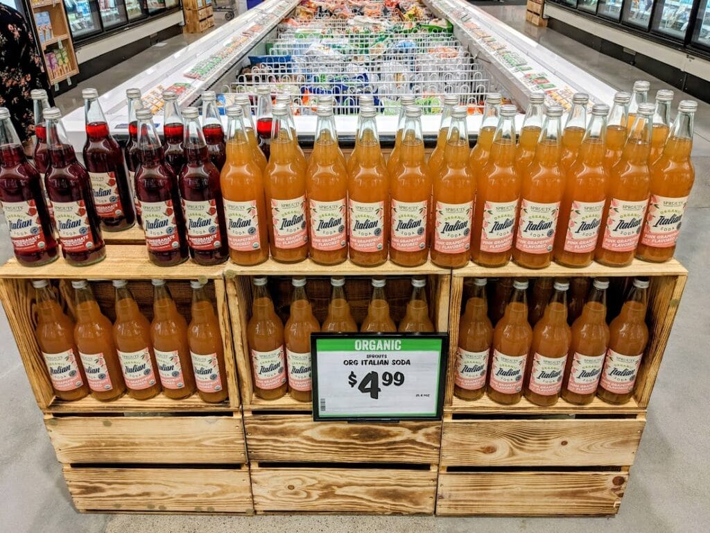 A display of Grapefruit and Pomegranate Organic Italian Sodas inside a Sprouts Farmers Market grocery store.