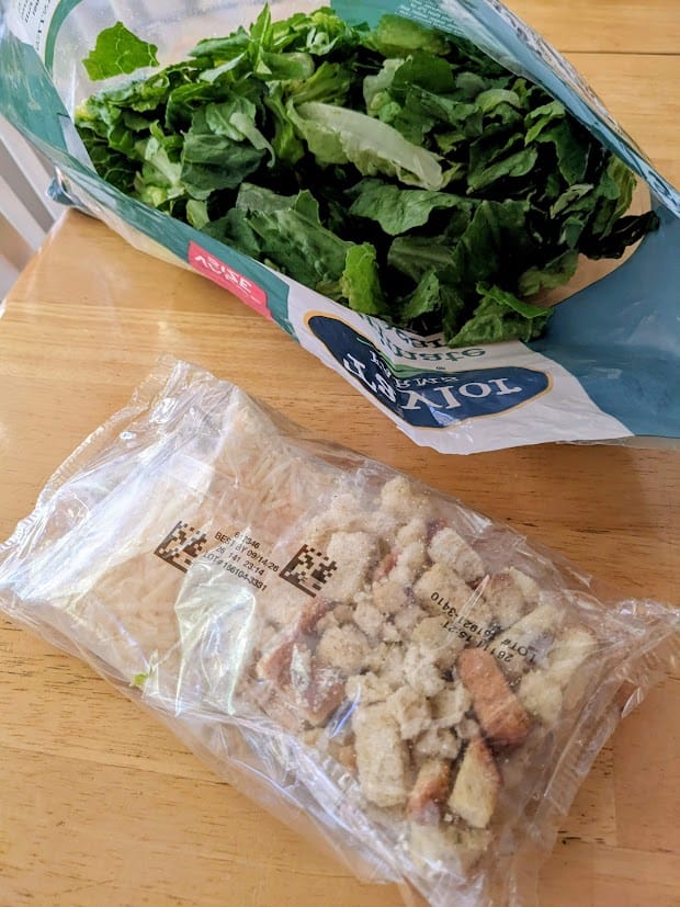 An open bag of Taylor Farms Ultimate Caesar Salad, with the packet of toppings removed.