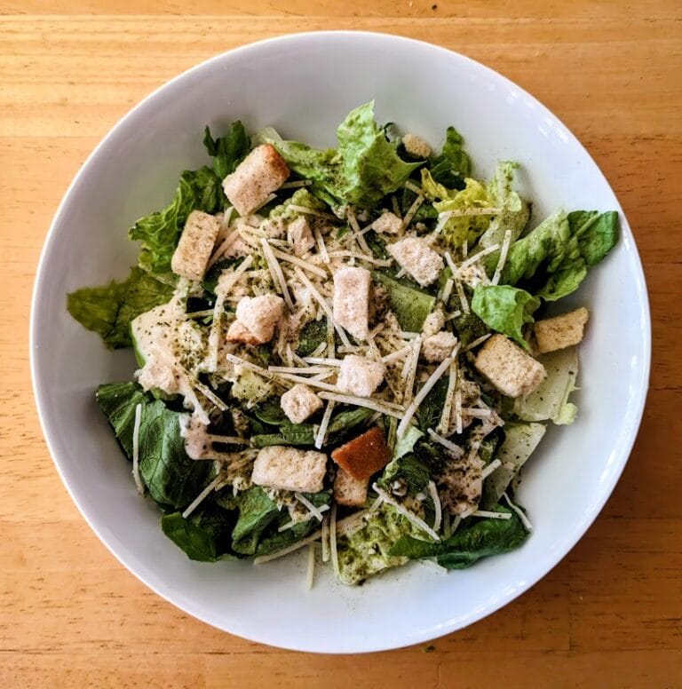 A white bowl with a serving of Taylor Farms Ultimate Caesar Salad from Costco.