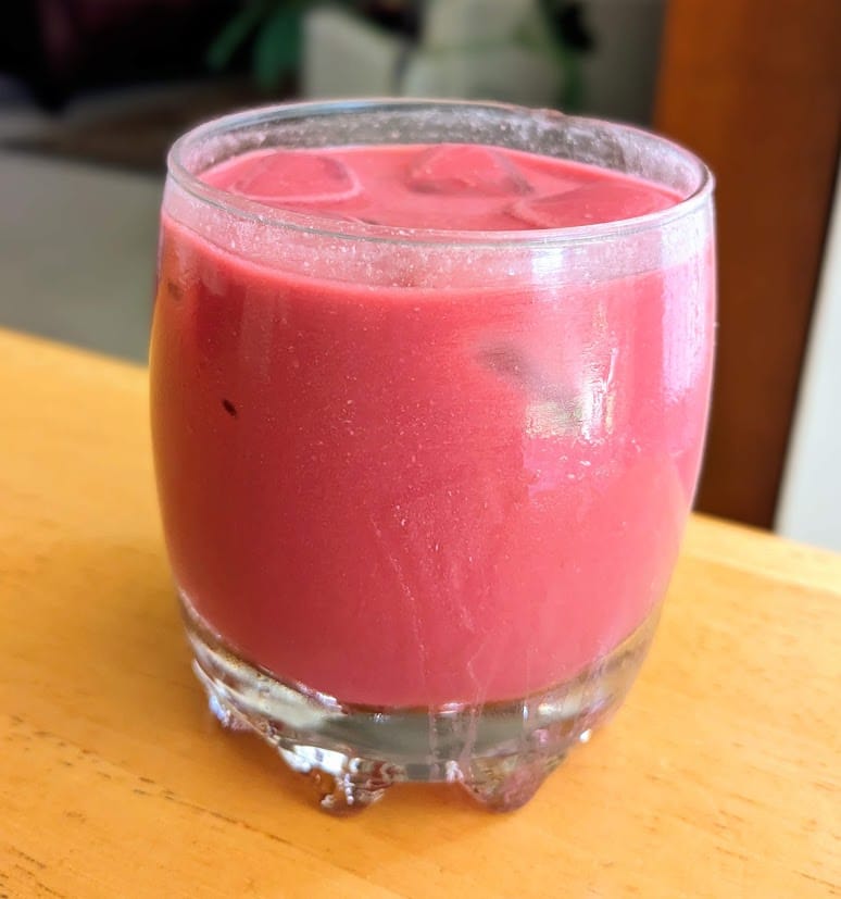 A dark pink cream soda in a clear glass made with Aldi Antioxidant Power Organic Juice.