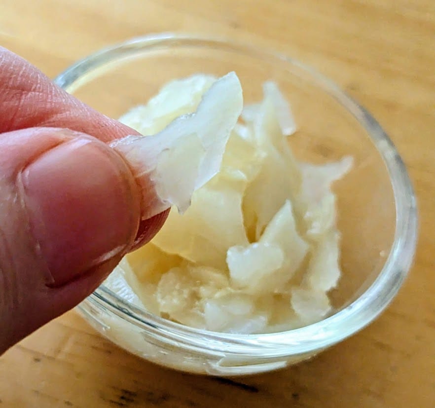 Fingers holding a piece of pickled ginger from a package of Costco Bento sushi.