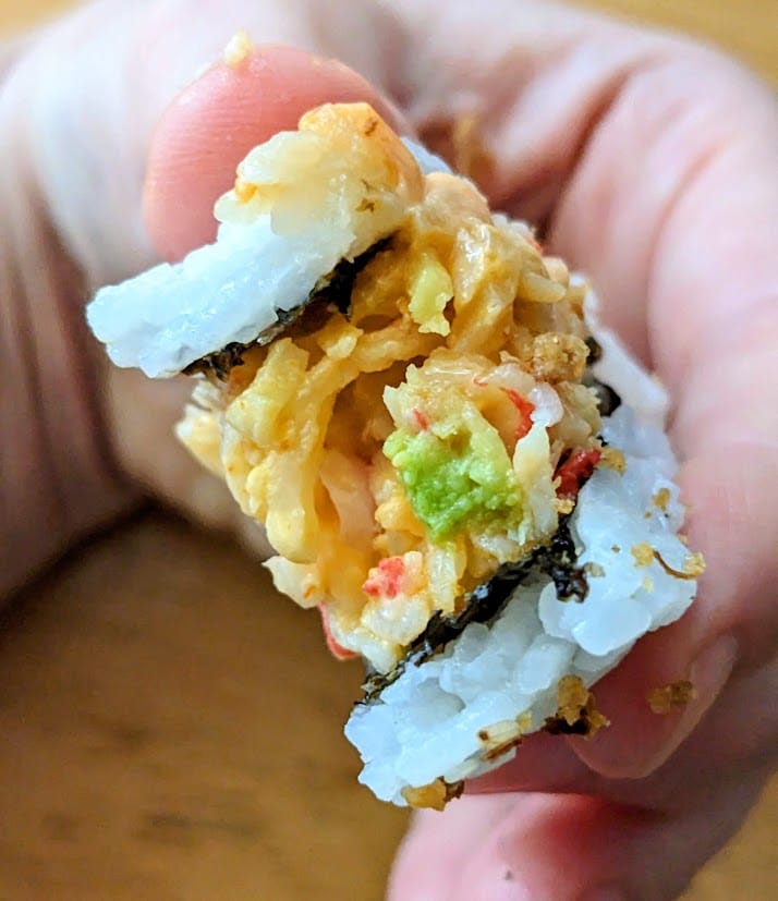 A bitten piece of Costco's California Crunch Sushi, showing the krab meat.