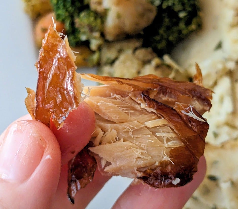 Fingers holding a chunk of smoked mackerel from a can of Fishwife seafood.