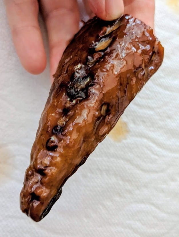 Fingers holding a piece of oily smoked mackerel from a can of Fishwife seafood.