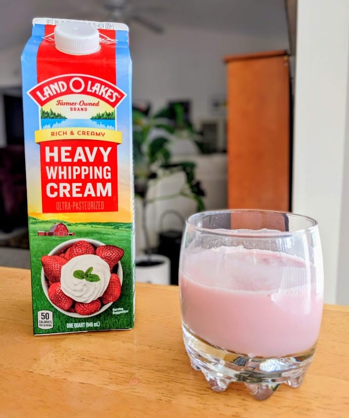 A quart of heavy whipping cream next to a glass of creme soda made with Jarritos Strawberry flavor.