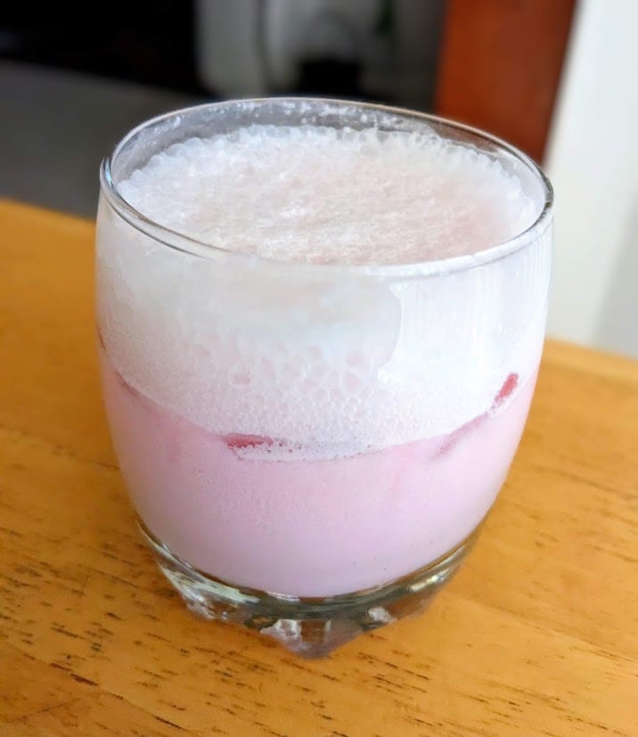 A glass with strawberry cream soda.