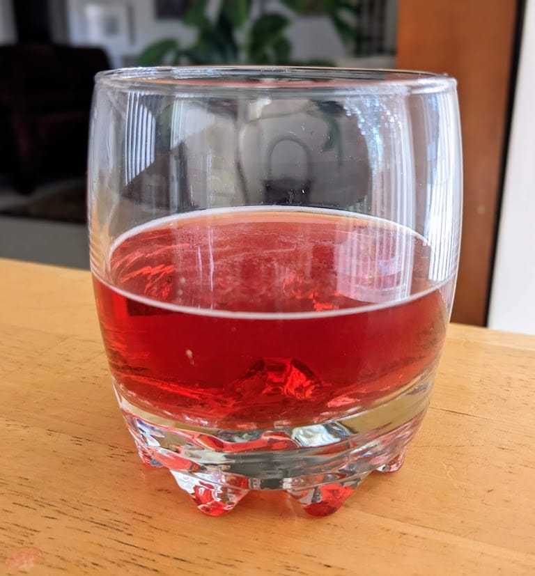 A clear glass with red Strawberry Soda from Jarritos.