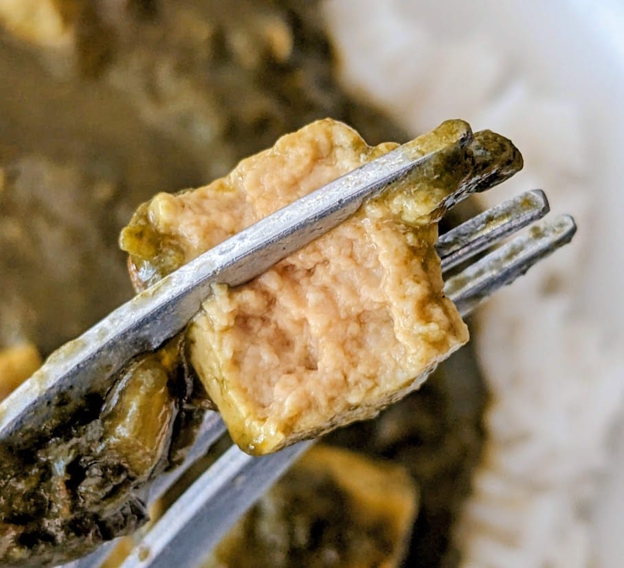 A fork holding a bitten cube of paneer from an MTR Minute Meal.