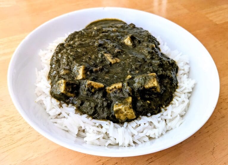 A white bowl with basmati rice topped with palak paneer from MTR Minute Meals.