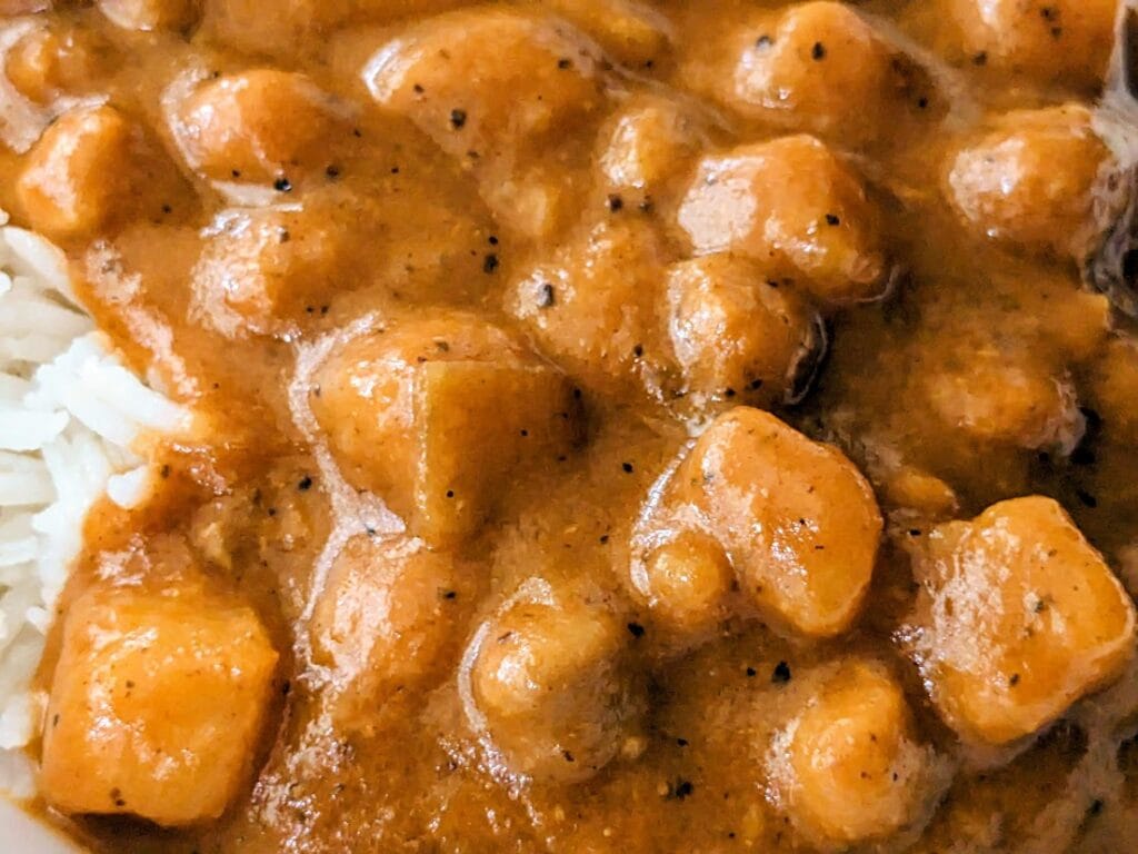 Detail of chickpeas and potatoes in coconut curry sauce from a Maya Kaimal madras meal.