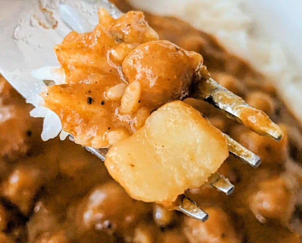 A fork with a bite of Maya Kaimal Madras Potato Curry with chickpeas.