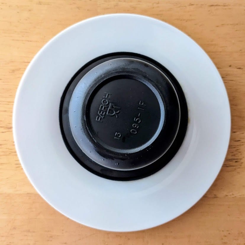 An inverted plastic cup of sticky toffee pudding from Costco on a white plate.