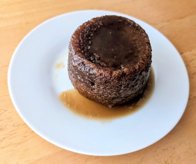 A white plate with a single-serve British Sticky Toffee Pudding Company Cake from Costco.