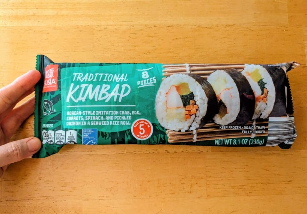 A hand holding a package of Aldi frozen Kimbap, Traditional flavor.
