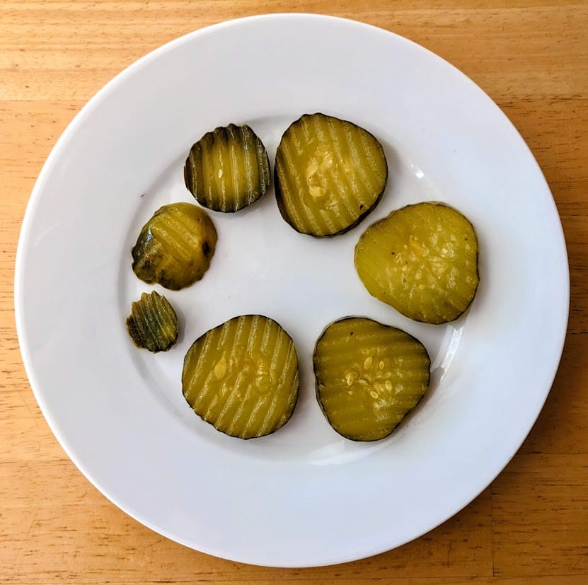A white plate with a circle of Bubbies Bread & Butter Pickles of various sizes.