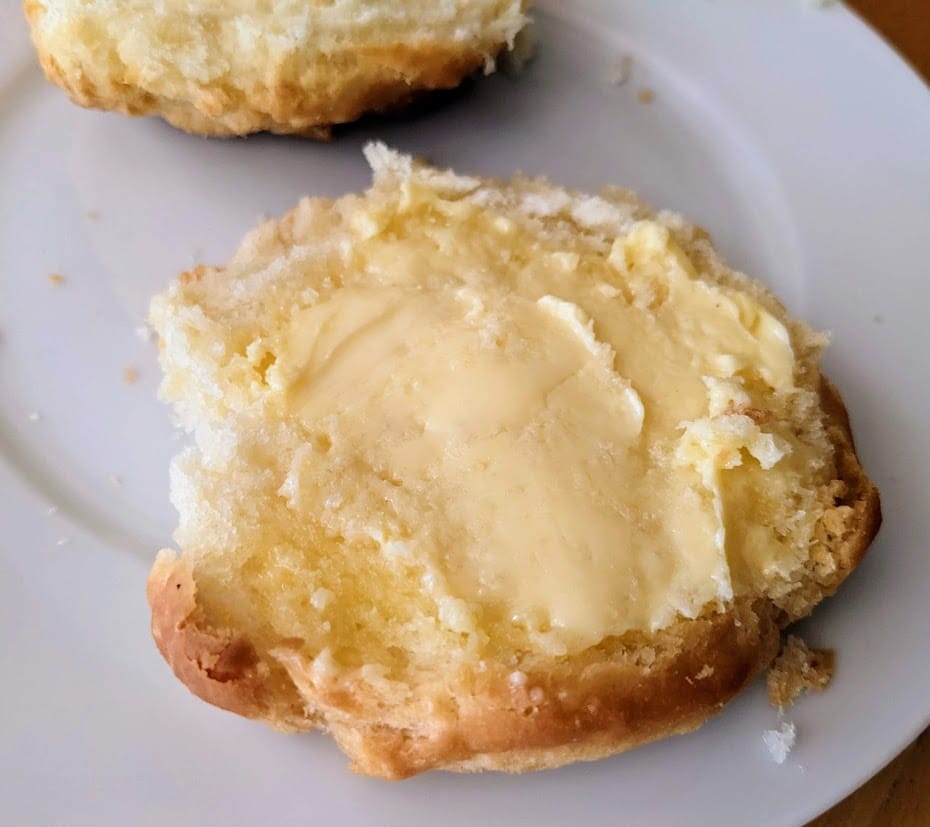Half a buttered Costco Bakery Buttermilk Biscuit on a plate.