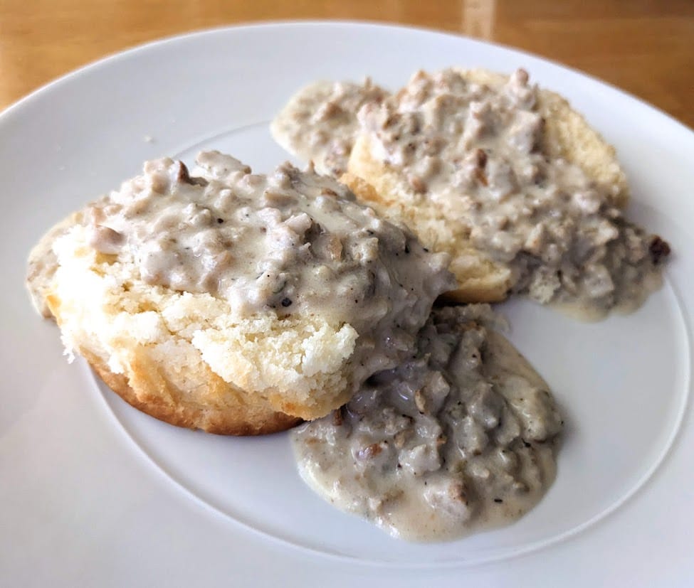 Two halves of a Costco Buttermilk Biscuit covered in sausage gravy.