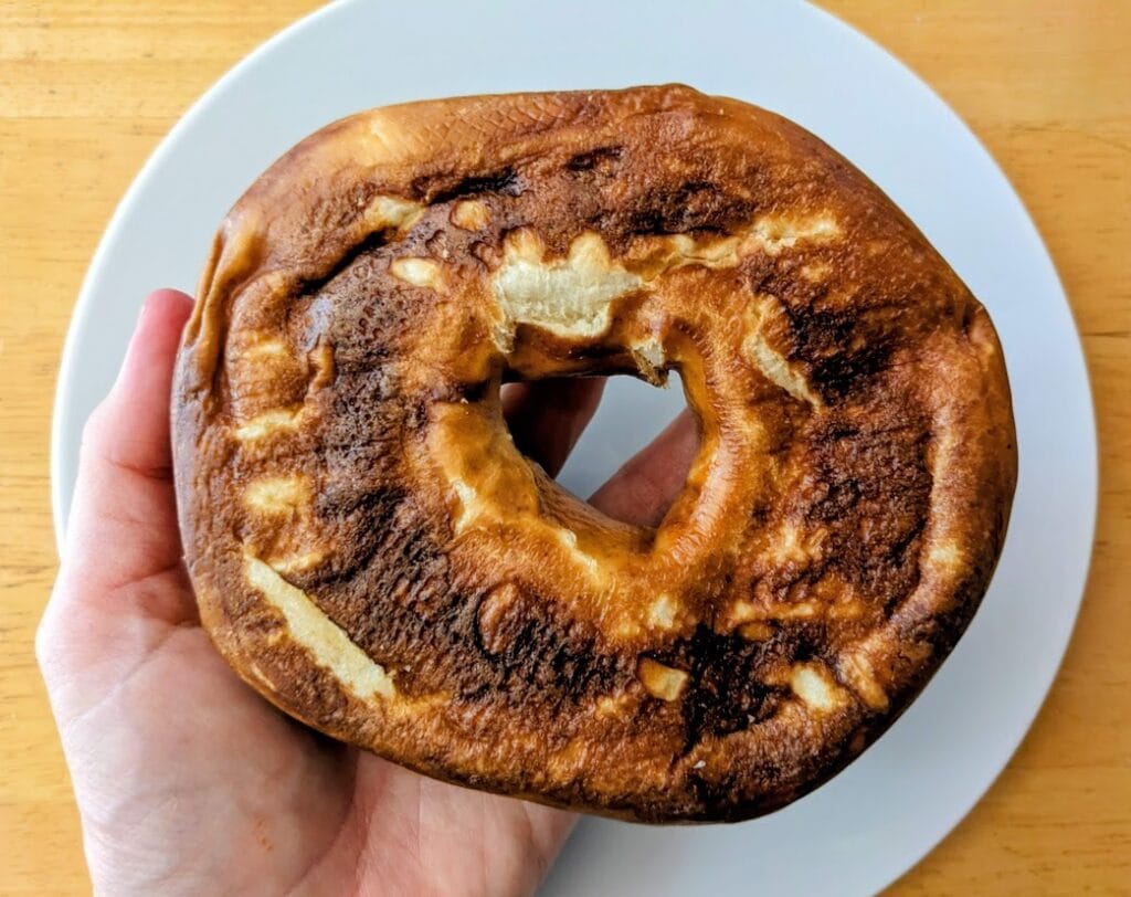 A hand holding the underside of a Costco Pretzel Bagel.