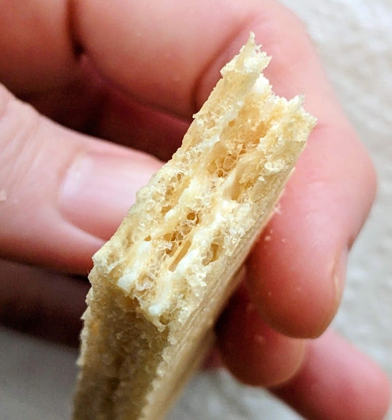 Fingers holding the bitten end of a Flora Lemon Wafer.
