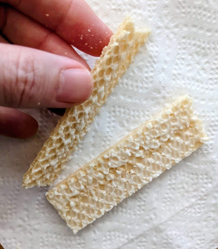 A hand peeling open layers of a lemon creme wafer cookie from Flora.