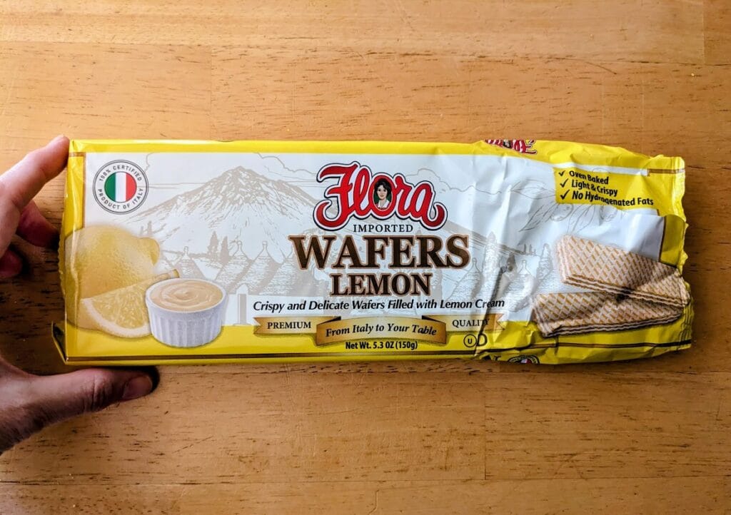A hand holding a package of Flora Italian Lemon Cream Wafers.