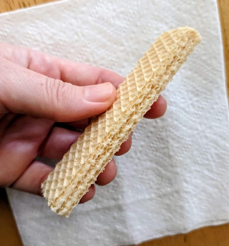 A hand holding a whole lemon creme wafer from Flora.