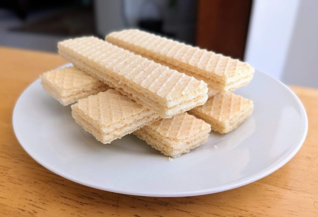 A small white plate with three stacked layers of Flora Italian Lemon Creme Wafers.