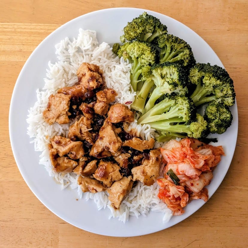 A plate with rice, chicken, broccoli, and Jongga Korean Kimchi.