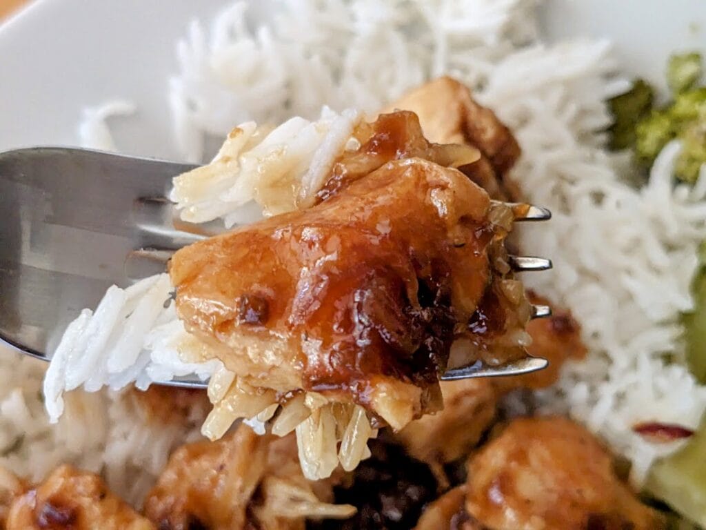 A fork holding a bite of basmati rice with Kevin's Hawaiian Style Chicken.