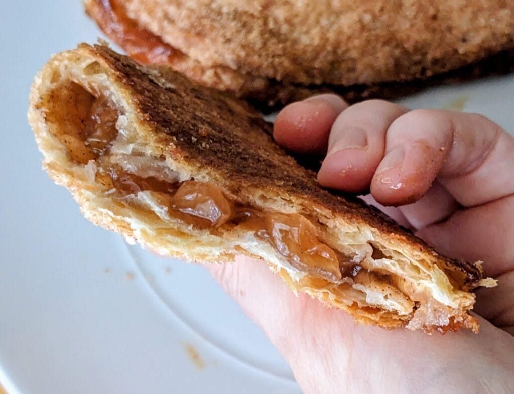 A hand holding part of an Apple Flip pastry from the Publix Bakery, showing the crust thickness.