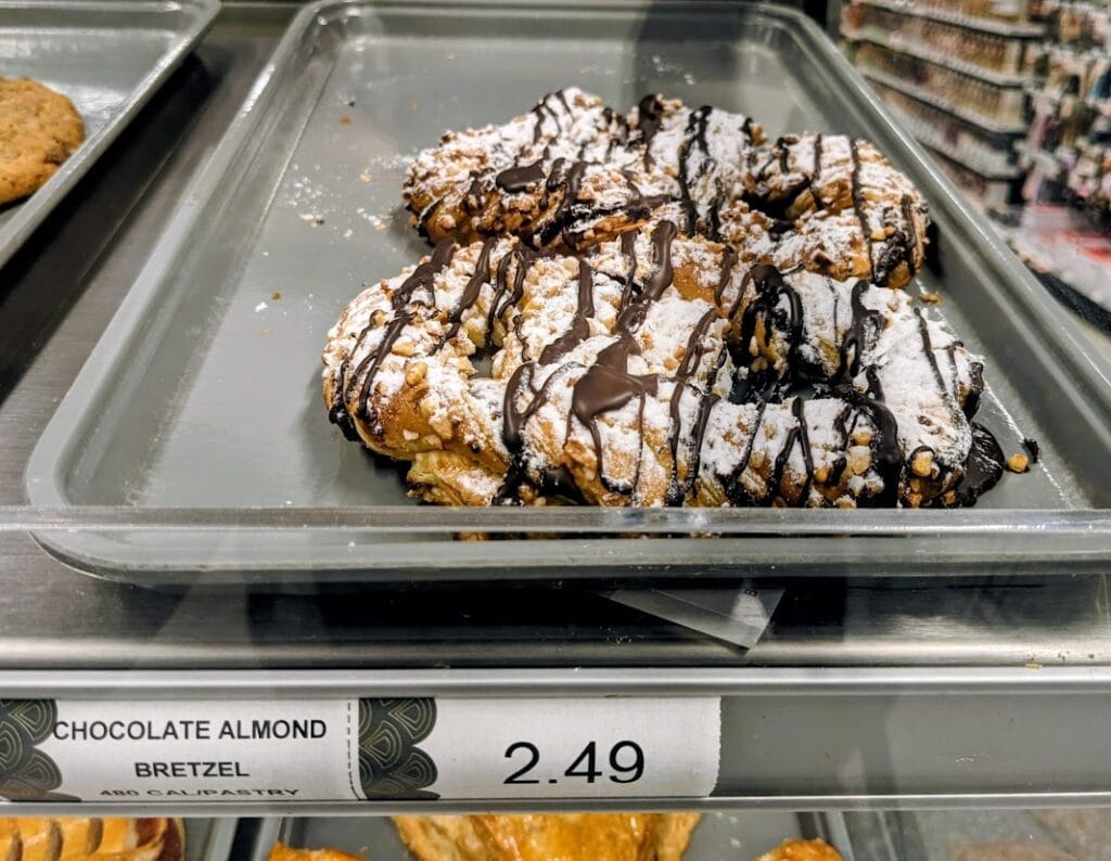 A Publix Bakery grab-and-go shelf with a tray of Chocolate Almond "Bretzel" pastries.