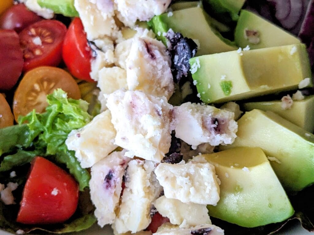 Close up of crumbled Somerdale Wensleydale & Blueberries cheese on top of a salad.