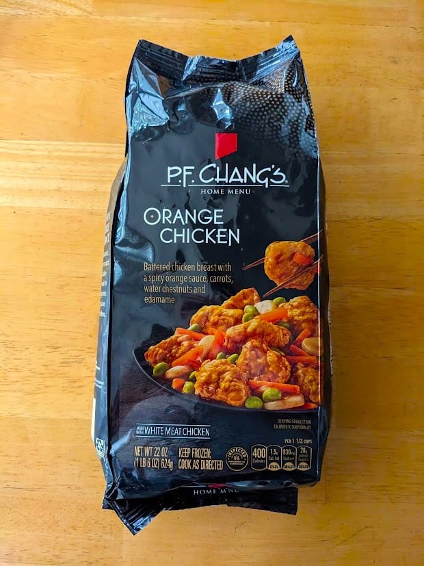 A bag of frozen PF Chang's Orange Chicken sitting on a kitchen table.