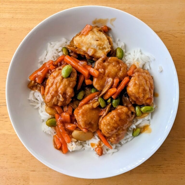 A white bowl of PF Chang's Home Menu Orange Chicken over basmati rice.