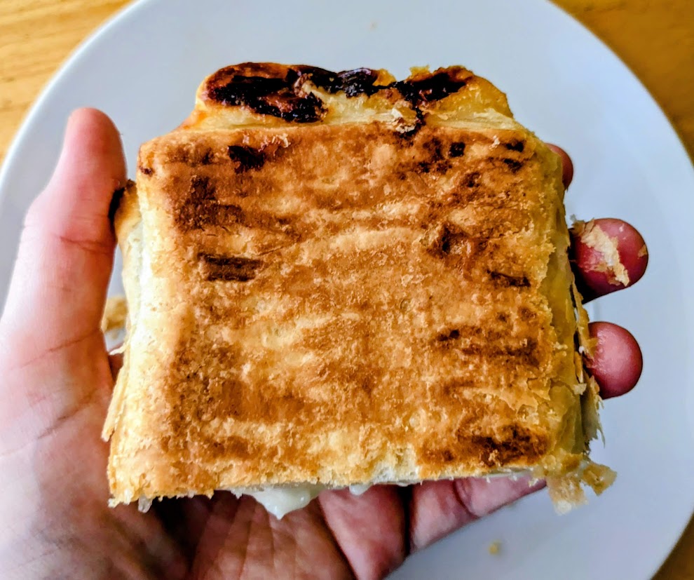A hand holding the underside of a baked Lemon Mascarpone Strudel from Aldi.